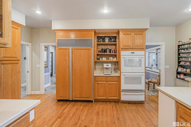 kitchen featuring paneled refrigerator, double oven, and light wood-type flooring