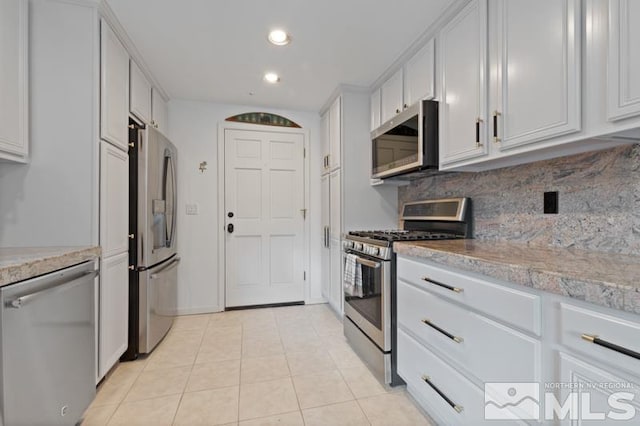 kitchen featuring white cabinetry, tasteful backsplash, light tile flooring, and stainless steel appliances