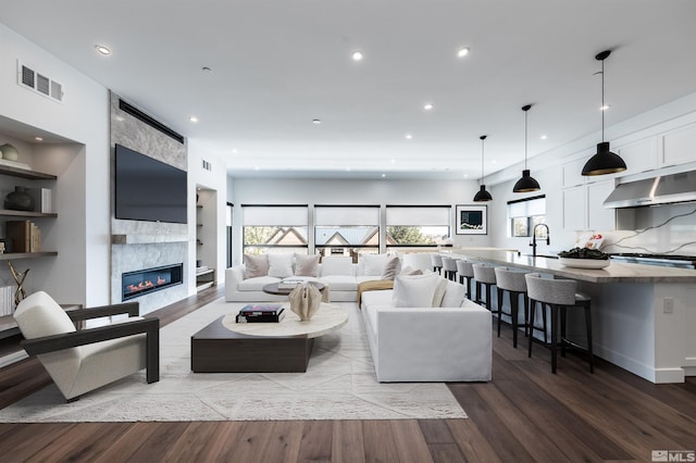 living room featuring light wood-type flooring, sink, and a large fireplace