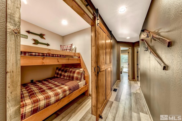 bedroom featuring a barn door and light hardwood / wood-style floors