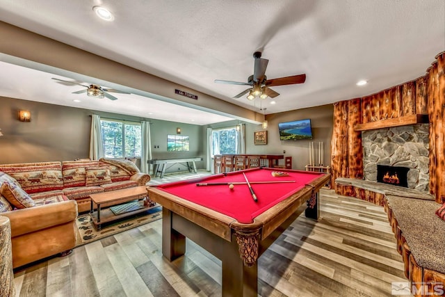 rec room with pool table, light hardwood / wood-style floors, ceiling fan, and a fireplace