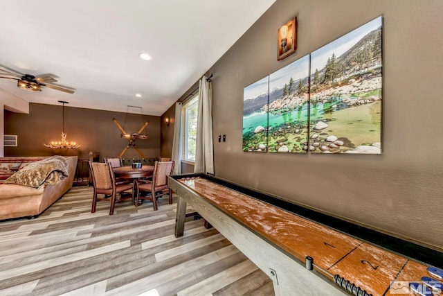 playroom with light hardwood / wood-style floors and ceiling fan with notable chandelier