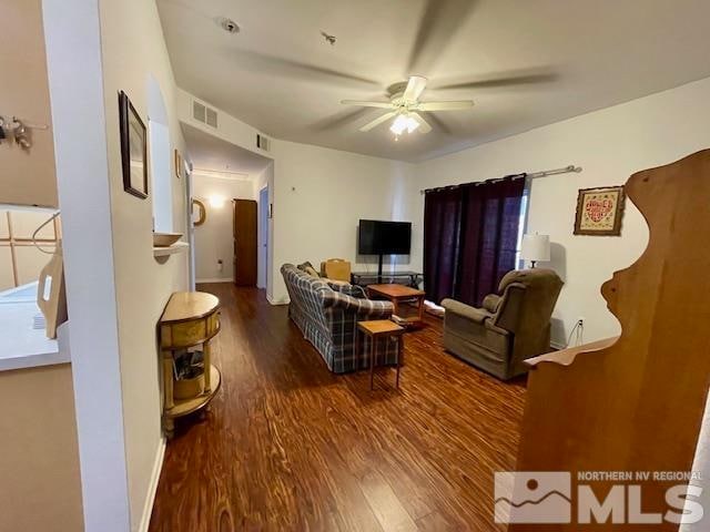 living room featuring dark wood-type flooring and ceiling fan