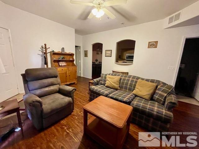 living room featuring dark wood-type flooring and ceiling fan