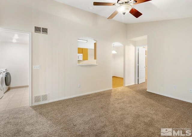 unfurnished room featuring ceiling fan, independent washer and dryer, light colored carpet, and high vaulted ceiling