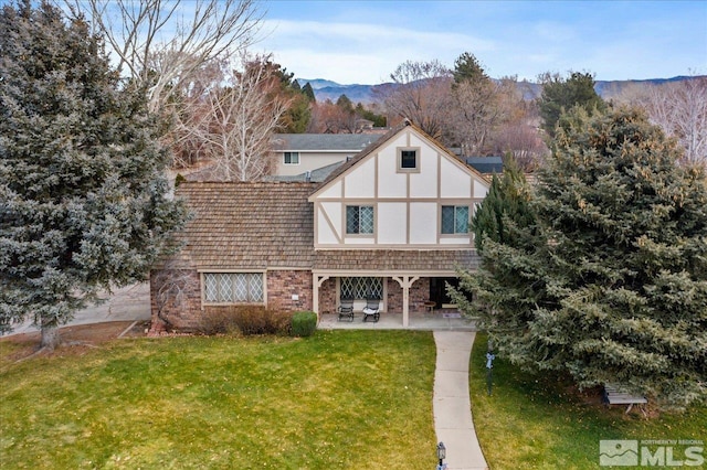 tudor-style house featuring a front yard and a patio