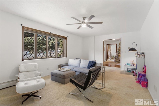 living room with ceiling fan, a baseboard heating unit, and light carpet