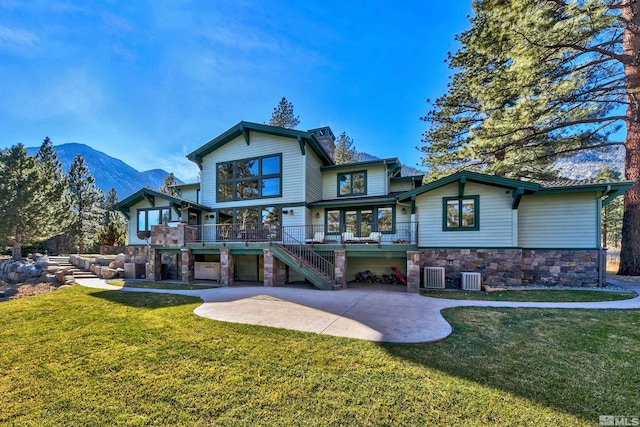 exterior space with a patio, a deck with mountain view, a front yard, and central AC unit