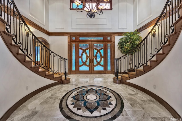 entryway featuring french doors, an inviting chandelier, and a towering ceiling