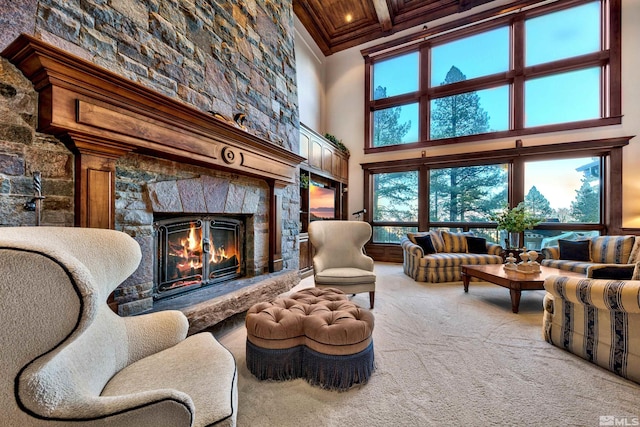 living room featuring beam ceiling, carpet flooring, a stone fireplace, and a towering ceiling