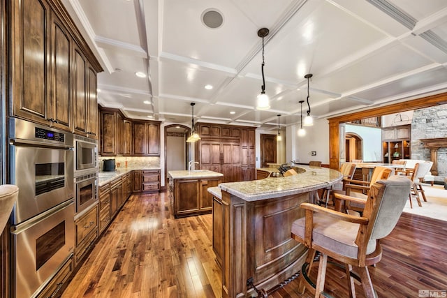 kitchen with decorative light fixtures, a spacious island, light stone counters, and stainless steel appliances