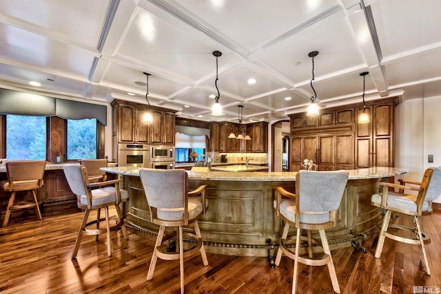 kitchen featuring dark hardwood / wood-style floors, a large island, a kitchen bar, and coffered ceiling