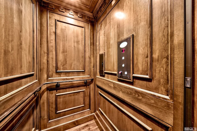 interior details with wooden walls, wood-type flooring, and elevator