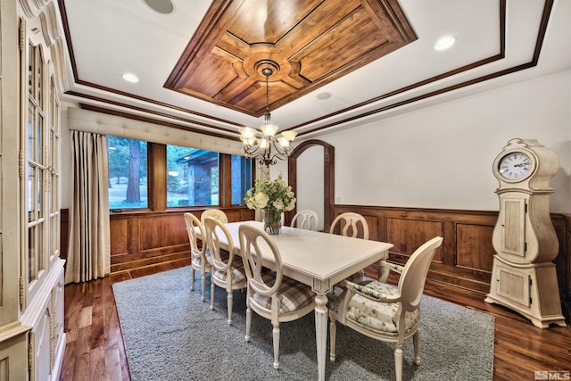 dining area featuring a raised ceiling, crown molding, a notable chandelier, and dark wood-type flooring