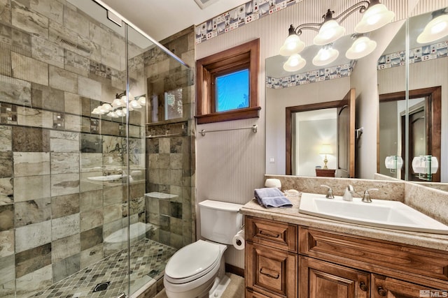 bathroom with an inviting chandelier, toilet, vanity, and a shower with shower door