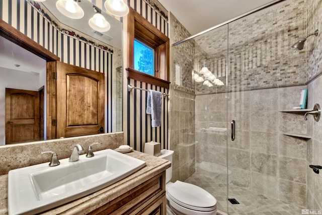 bathroom featuring an enclosed shower, toilet, and vanity