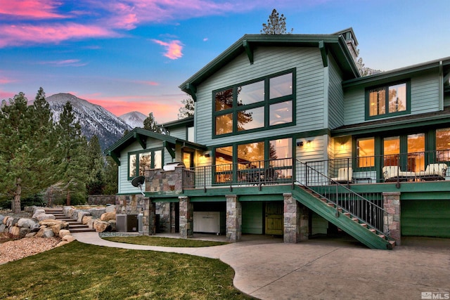 view of front of house featuring a lawn, central AC unit, and a mountain view