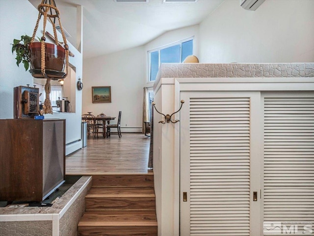 stairs featuring a baseboard radiator, dark wood-type flooring, and a wealth of natural light