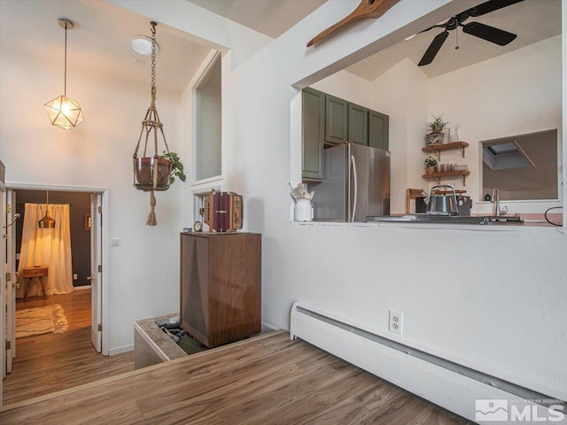 living room with ceiling fan, baseboard heating, and wood-type flooring