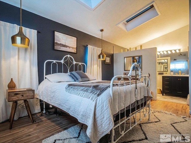 bedroom with vaulted ceiling with skylight, sink, and light wood-type flooring