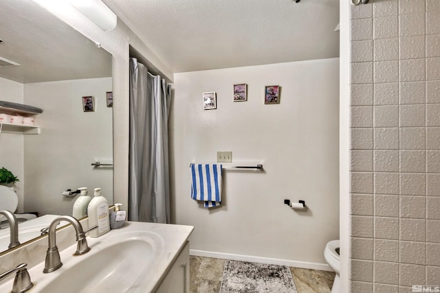 bathroom featuring vanity, a textured ceiling, tile floors, and toilet