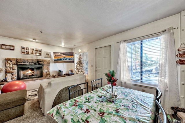 carpeted dining area featuring a fireplace and a textured ceiling