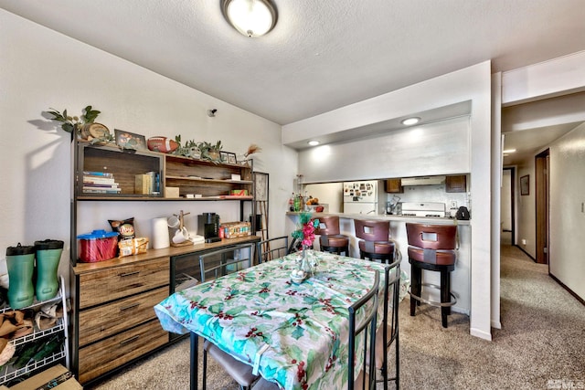 carpeted dining room with a textured ceiling