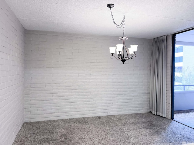 unfurnished room with brick wall, a wealth of natural light, and an inviting chandelier