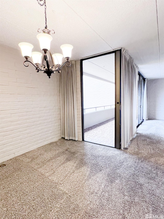 unfurnished dining area featuring a wealth of natural light, brick wall, a chandelier, and a textured ceiling