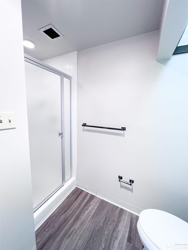 bathroom with a shower with shower door, hardwood / wood-style floors, and toilet