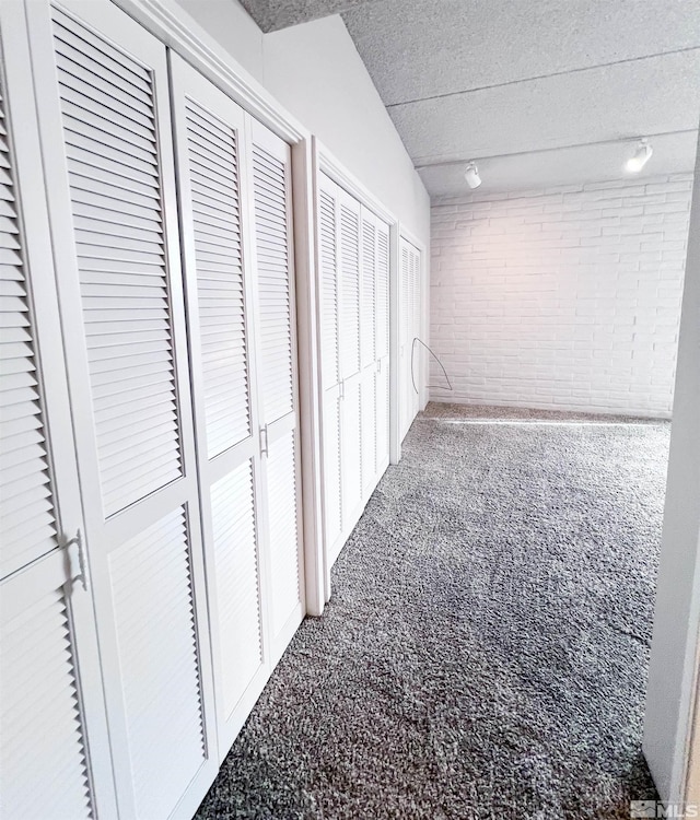 corridor featuring brick wall and carpet