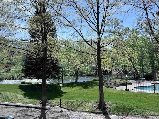 view of home's community with a water view, a pool, and a yard