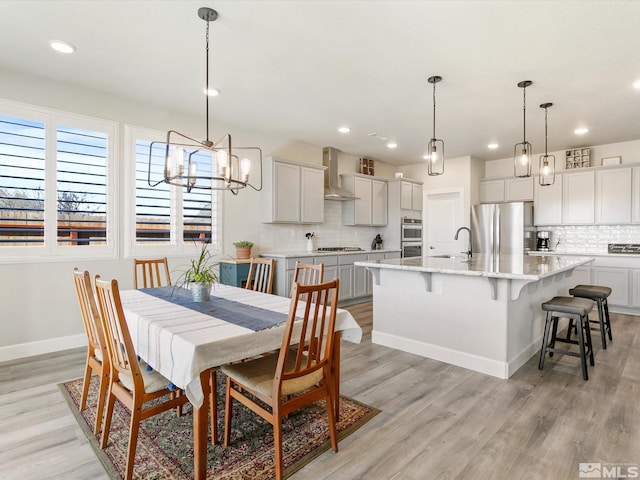 dining area with light hardwood / wood-style floors, a notable chandelier, and sink