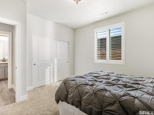 bedroom with light carpet, a closet, and ensuite bathroom