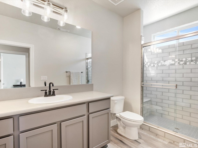 bathroom with toilet, vanity with extensive cabinet space, walk in shower, and hardwood / wood-style flooring