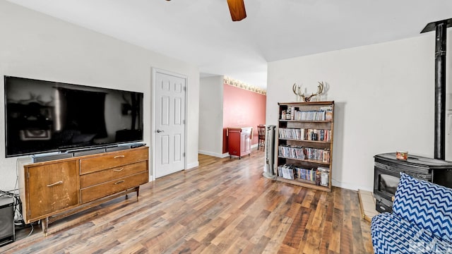 living room with a wood stove, ceiling fan, and hardwood / wood-style flooring