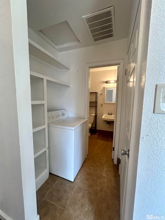 washroom with sink, washer / dryer, and dark tile floors