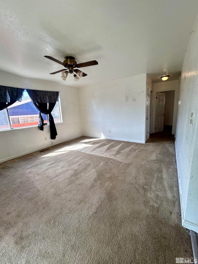 spare room with ceiling fan and dark carpet