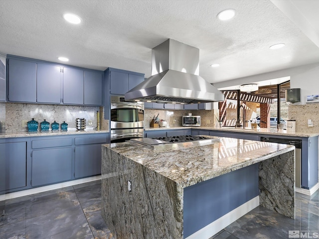 kitchen with island exhaust hood, light stone counters, a kitchen island, appliances with stainless steel finishes, and backsplash