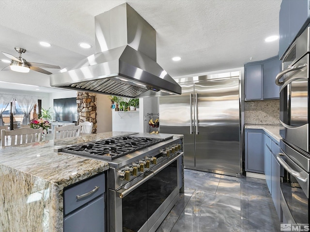 kitchen featuring high quality appliances, backsplash, light stone countertops, and island exhaust hood