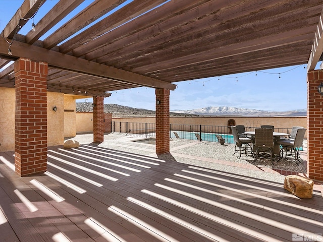 snow covered patio featuring a pergola, a mountain view, and a fenced in pool