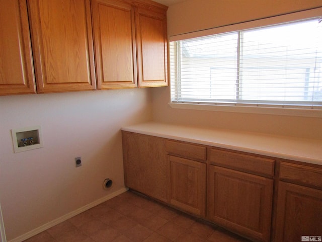 washroom featuring washer hookup, electric dryer hookup, dark tile floors, and cabinets