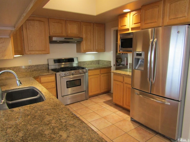 kitchen featuring light tile flooring, stone countertops, appliances with stainless steel finishes, and sink