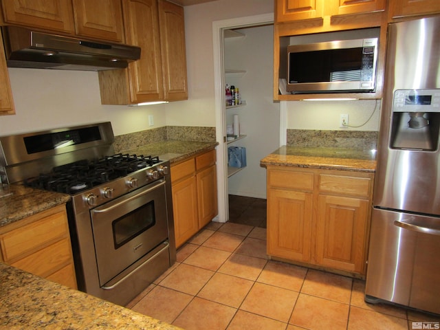 kitchen featuring stone counters, stainless steel appliances, and light tile floors