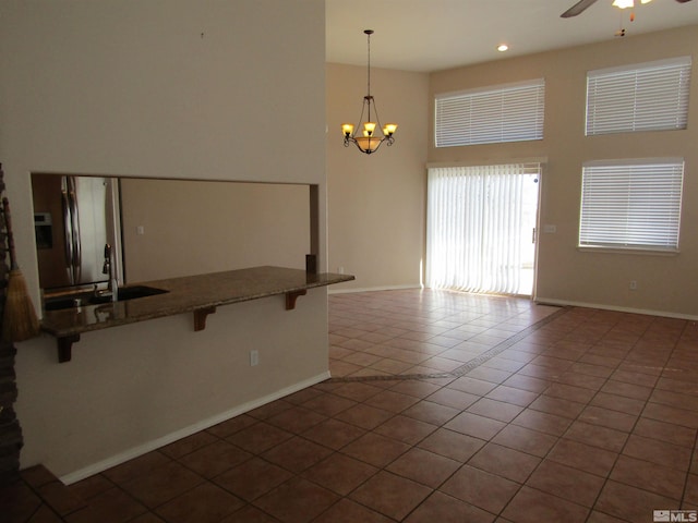 interior space featuring a high ceiling, dark tile floors, and ceiling fan with notable chandelier