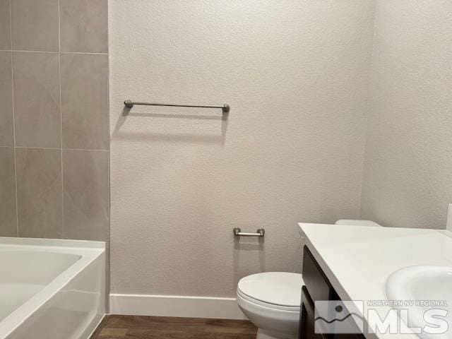 bathroom with vanity, wood-type flooring, a bathing tub, and toilet