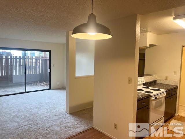 kitchen with electric range, a textured ceiling, light wood-type flooring, dark stone countertops, and decorative light fixtures