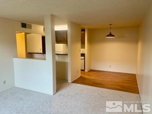 unfurnished room with a textured ceiling and light hardwood / wood-style floors