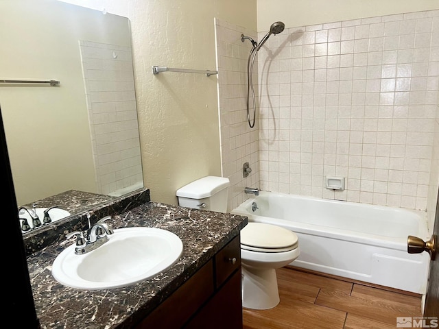 full bathroom with vanity, tiled shower / bath combo, hardwood / wood-style flooring, and toilet