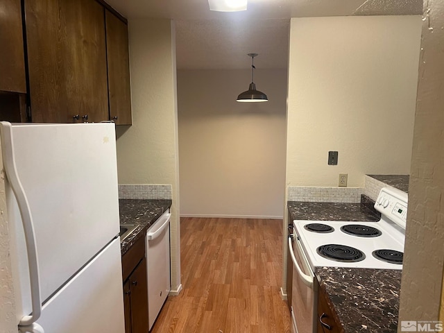 kitchen featuring dark stone countertops, light hardwood / wood-style floors, dark brown cabinetry, decorative light fixtures, and white appliances